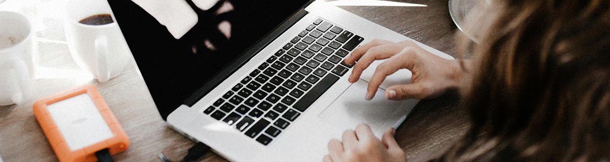 jeune femme à droite vue de l'arrrière en train de manipuler le teckpad de son macbook portable