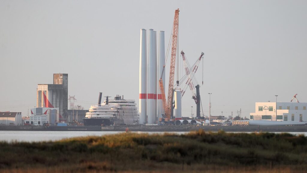 Photo prise de la rive sud de l'estuaire de la Loire montrant les chantiers de l'Atlantique et les mâts du champ éolien de Noirmoutier